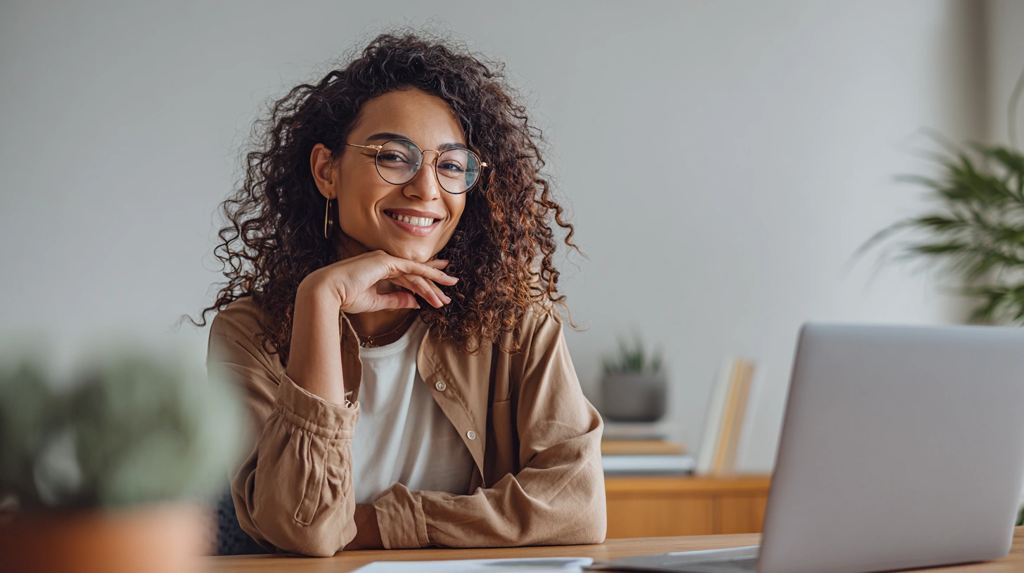 En person som sitter vid ett skrivbord och genomför en lyckad digital intervju med ett leende.